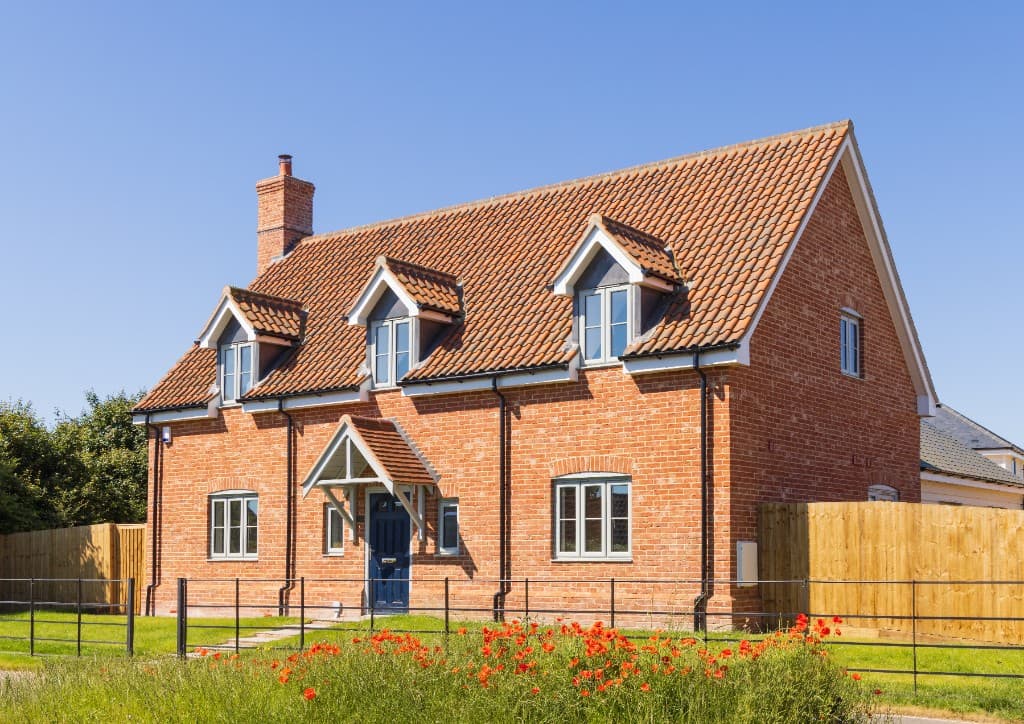 UK detached new-build home with feature windows, brick front and summer garden
